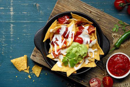 bowl of corn chips nachos with tomato sauce and melted cheese, top view