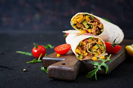 Burritos wraps with beef and vegetables on black background. Beef burrito, mexican food.