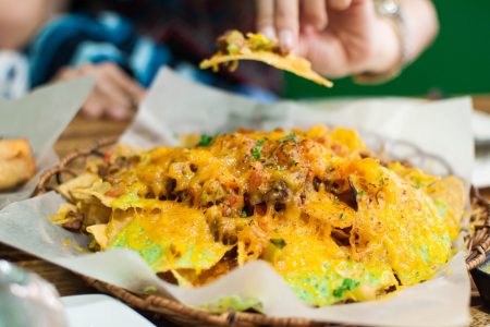 A close-up of plate full of cheesy nachos on a wooden table