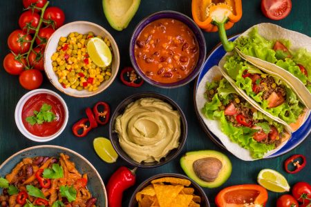 Mixed mexican food. Party food. Guacamole, nachos, fajita, meat tacos, salsa, peppers, tomatoes on a wooden table. Top view. Tex-mex cuisine. Assorted appetizers. Cuisine of Mexico